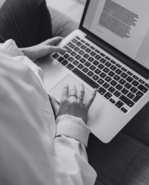 A person seated on a couch, focused on their laptop, creating a content.